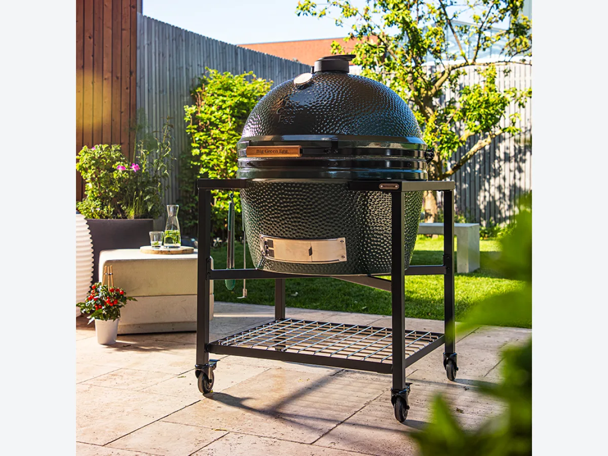 Big Green Egg Modular EGG Workspace, Close-up van een EGG Frame met Big Green Egg Large op een terras met tuinmeubelen