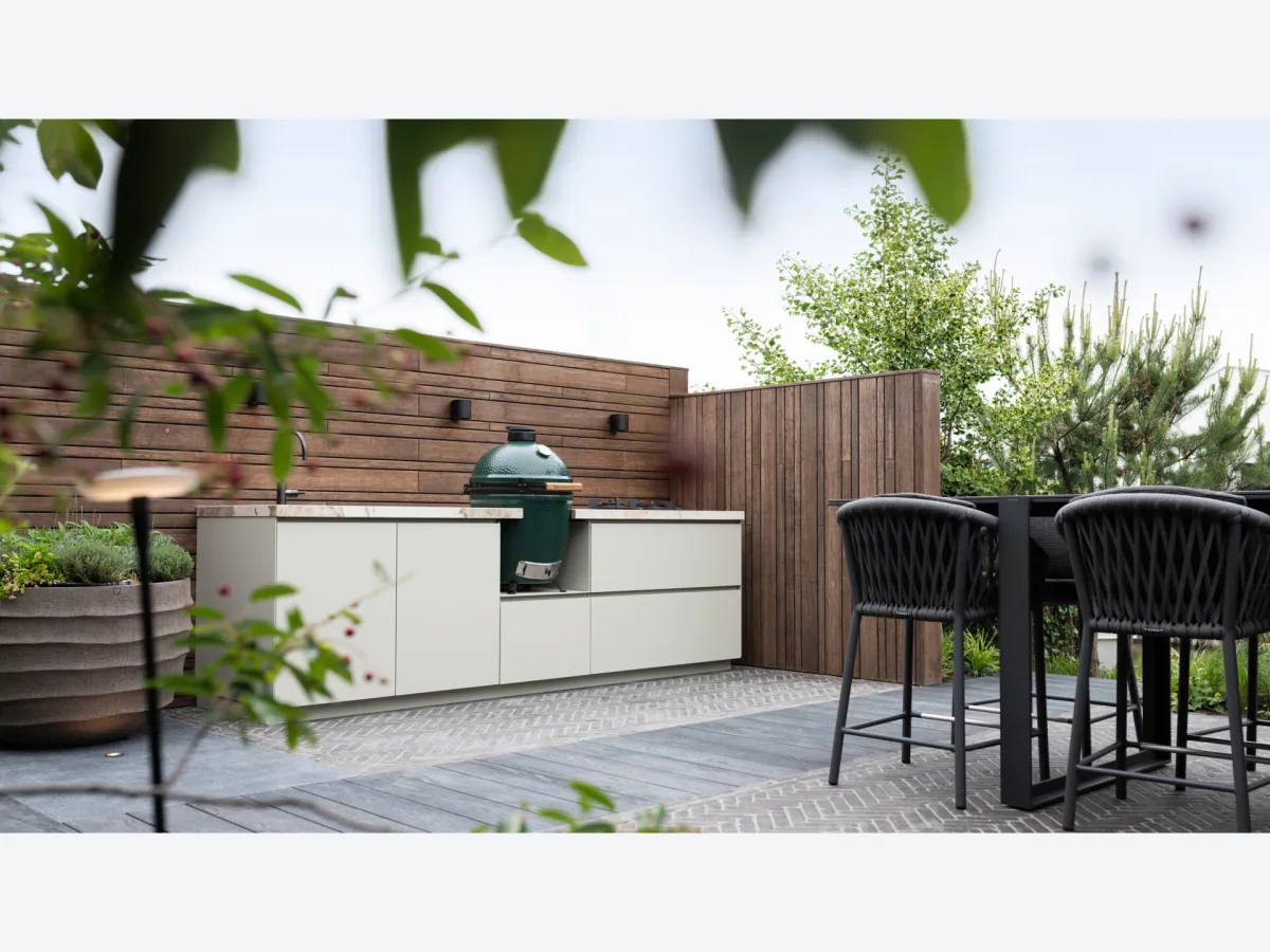COOXS Create, Maatwerk buitenkeuken in lichte kleur met Big Green Egg en gaspitten tegen een houten wand in Naaldwijk