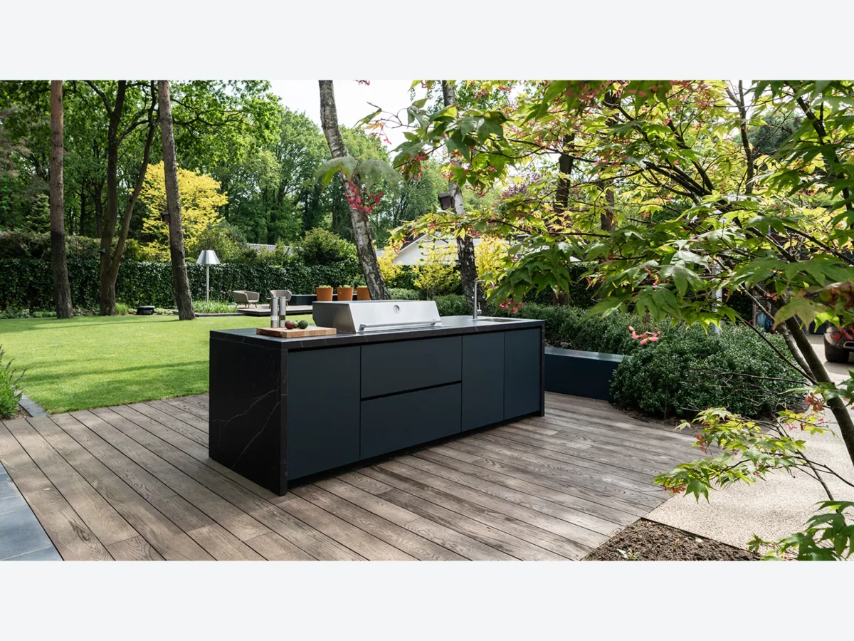 COOXS Create, Zwarte maatwerk eilandkeuken met gasbarbecue op een houten vlonder in een bostuin in Soest
