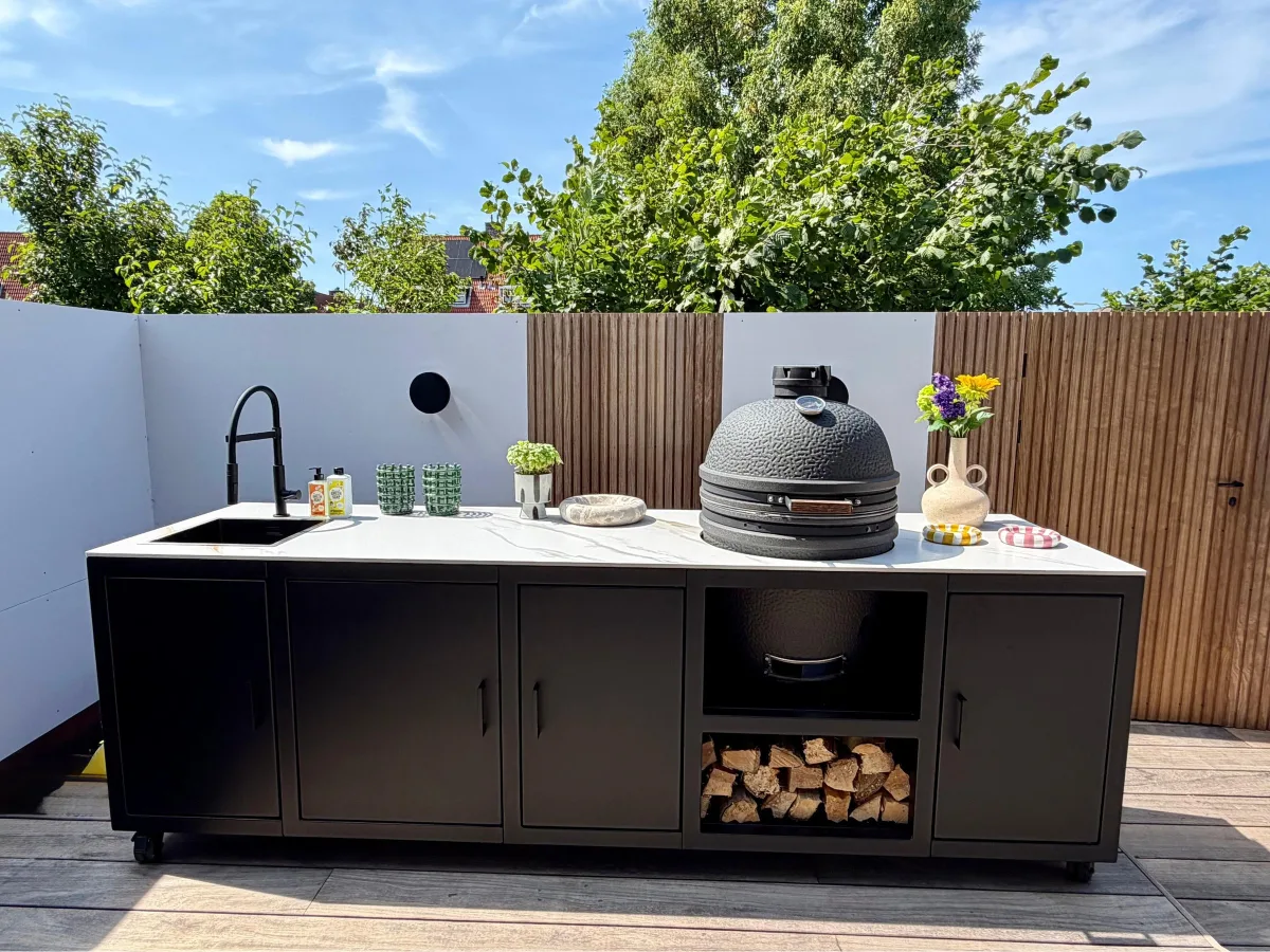 Fieldsman Modulaire buitenkeuken, Zwarte modulaire buitenkeuken met Calacatta Gold werkblad, spoelbak, kamado en houtopslag op een vlonder (portfolio Haarlem)