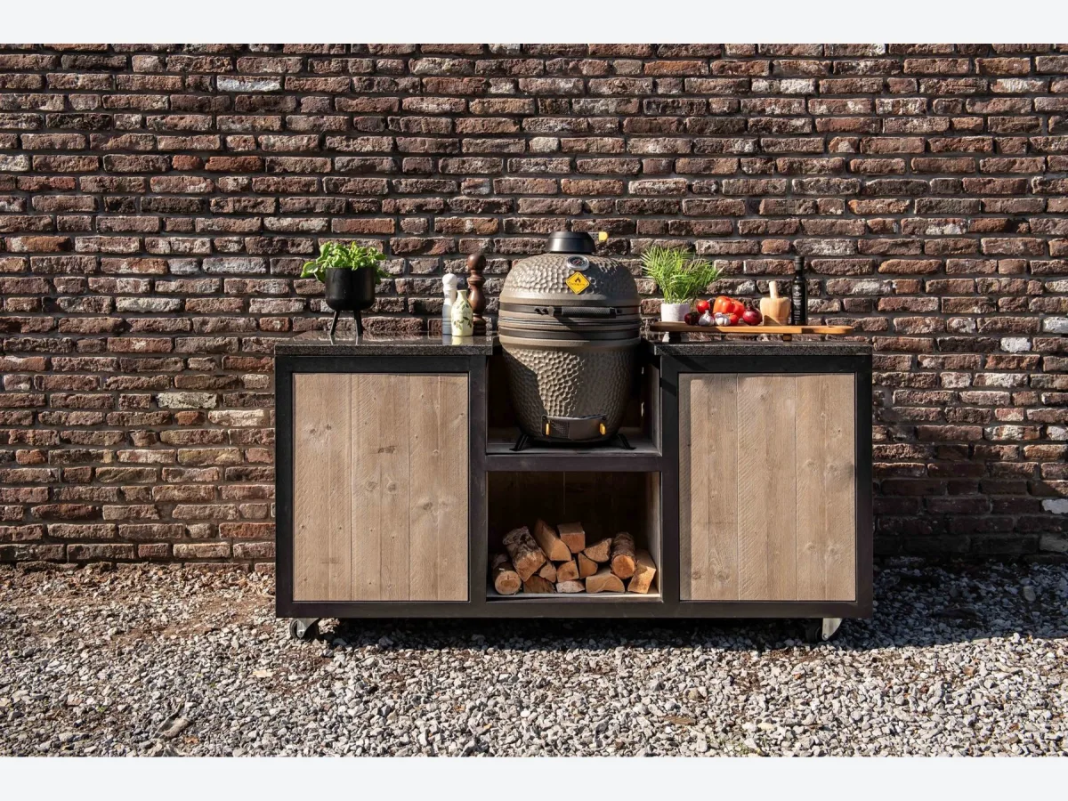 HoutenmeubelsXL Kanawa, Buitenkeuken Kanawa 180 cm met zwart stalen frame, steigerhouten fronten en een kamado in het middenvak, recht van voren voor een bakstenen muur