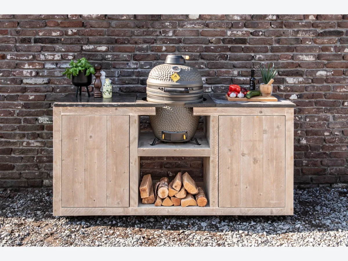 HoutenmeubelsXL Madura, Buitenkeuken Madura 180 cm van steigerhout met hardstenen tegels en een kamado in het middenvak, recht van voren voor een bakstenen muur