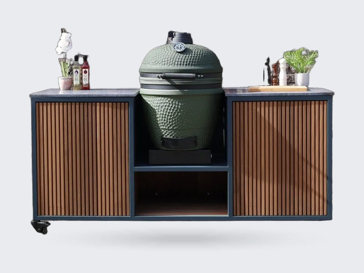HoutenmeubelsXL Moddern, Buitenkeuken Moddern van thermohout met antraciet stalen frame en de meegeleverde Moddern kamado in het middenvak, recht van voren voor een bakstenen muur