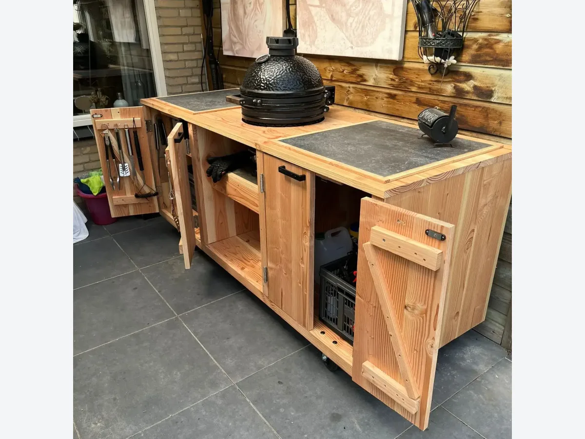 Maison DAM 3 delen, Buitenkeuken 3 delen van douglashout met keramische tegels en zwarte kamado, deuren open, onder een overkapping