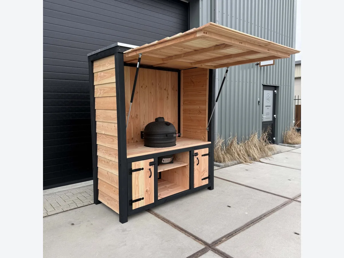 Maison DAM Douglas deluxe met klep, Douglas buitenkeuken deluxe met geopende klep, zwart frame en kamado, driekwart van linksvoor voor een donkere loods