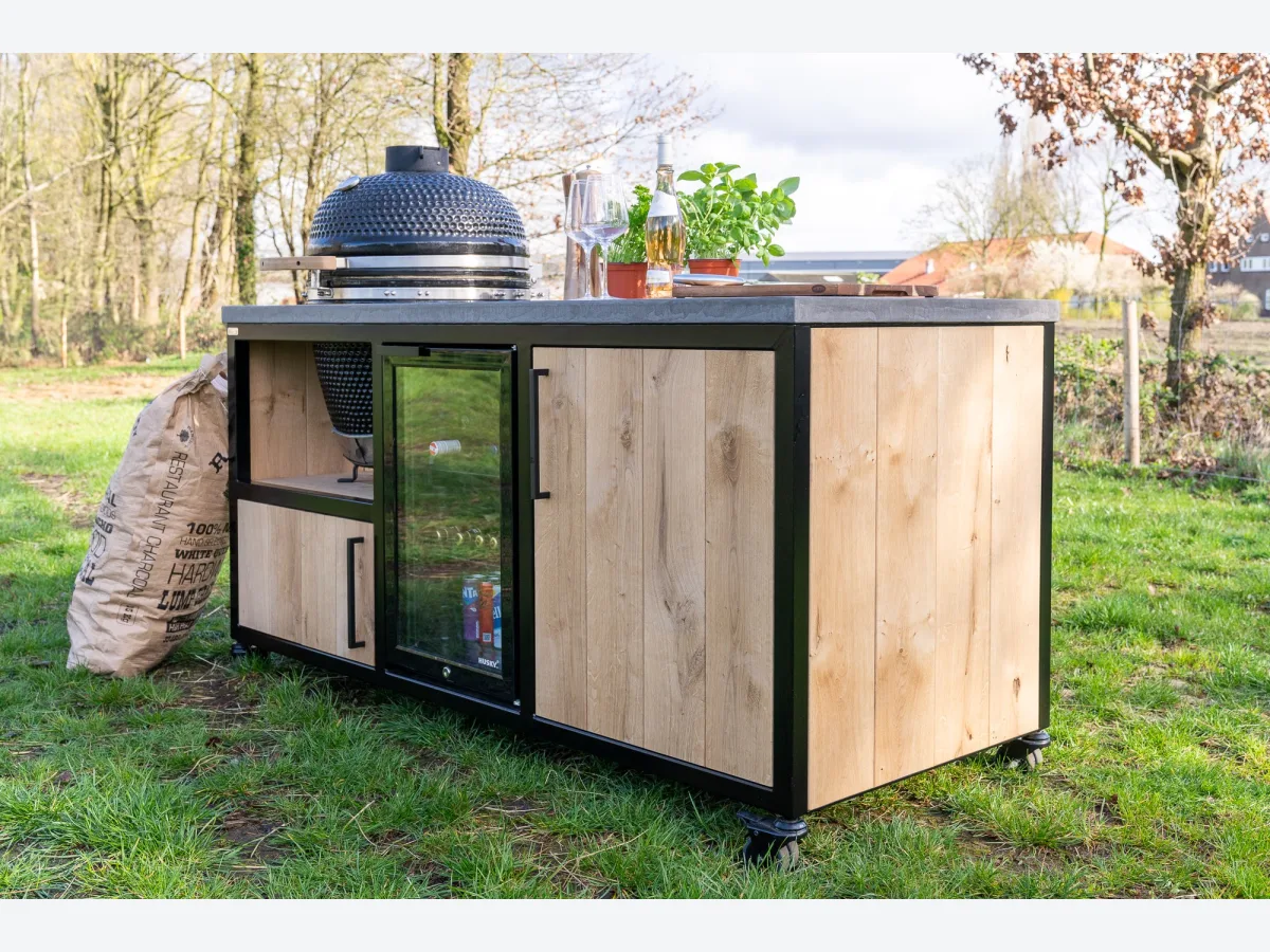 MB Industrial Living Basic, Buitenkeuken Basic met kamado, inbouwkoelkast en houten deur, driekwart van linksvoor in het gras