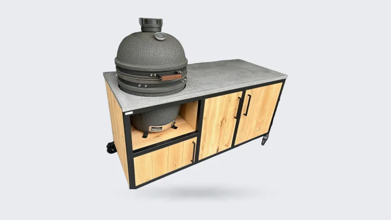 MB Industrial Living Basic, Buitenkeuken Basic met zwart stalen frame, eiken fronten en grijs Mortex werkblad, kamado links en twee houten deuren, driekwart van linksvoor op een overdekt terras