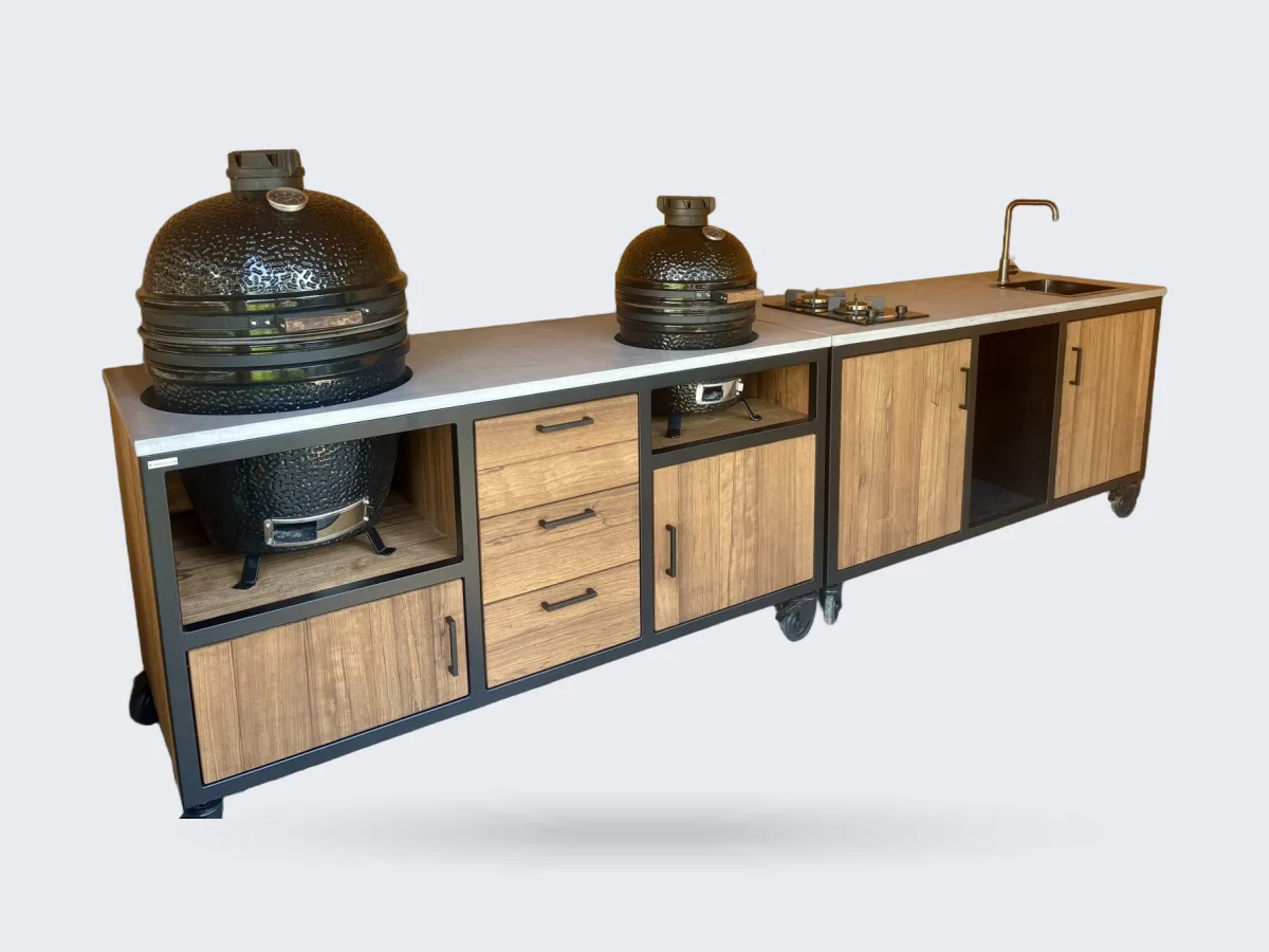 MB Industrial Living Maatwerk buitenkeuken, Maatwerk buitenkeuken met zwart stalen frame, eiken fronten en grijs werkblad, twee kamados, kookplaat en spoelbak, in een houten veranda