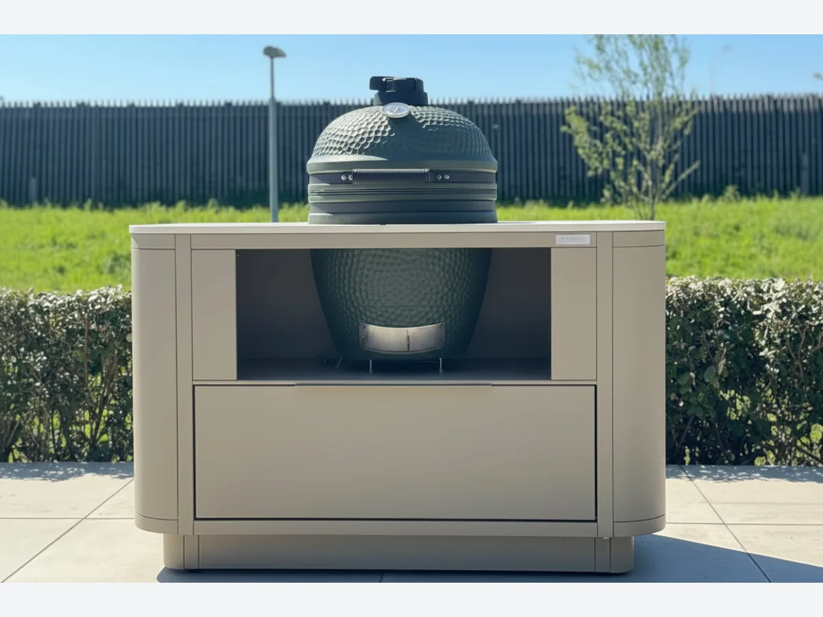 Rêveluxe Origine, Showmodel Origine Oval in taupe met Marmorio werkblad en Big Green Egg op een terras naast een gazon (1248 px breed, groter niet op de site)