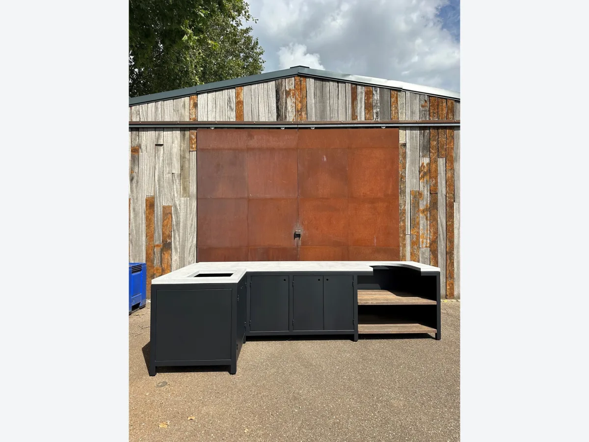 Robuust Maatwerk Vaste buitenkeuken, Hoekbuitenkeuken van zwart staal met betonnen blad, azobe leggers en uitsparing voor een kamado, zonder kamado, op het terrein van de maker