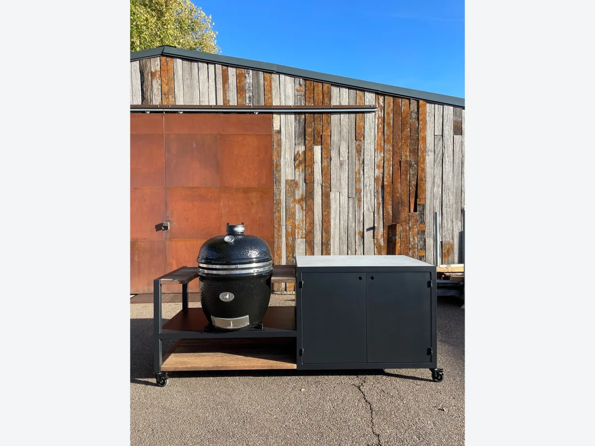 Robuust Maatwerk Verrijdbare buitenkeuken, Verrijdbare stalen buitenkeuken met kast, betonnen blad en kamado op een stalen plateau, voor een wand van cortenstaal en oud hout