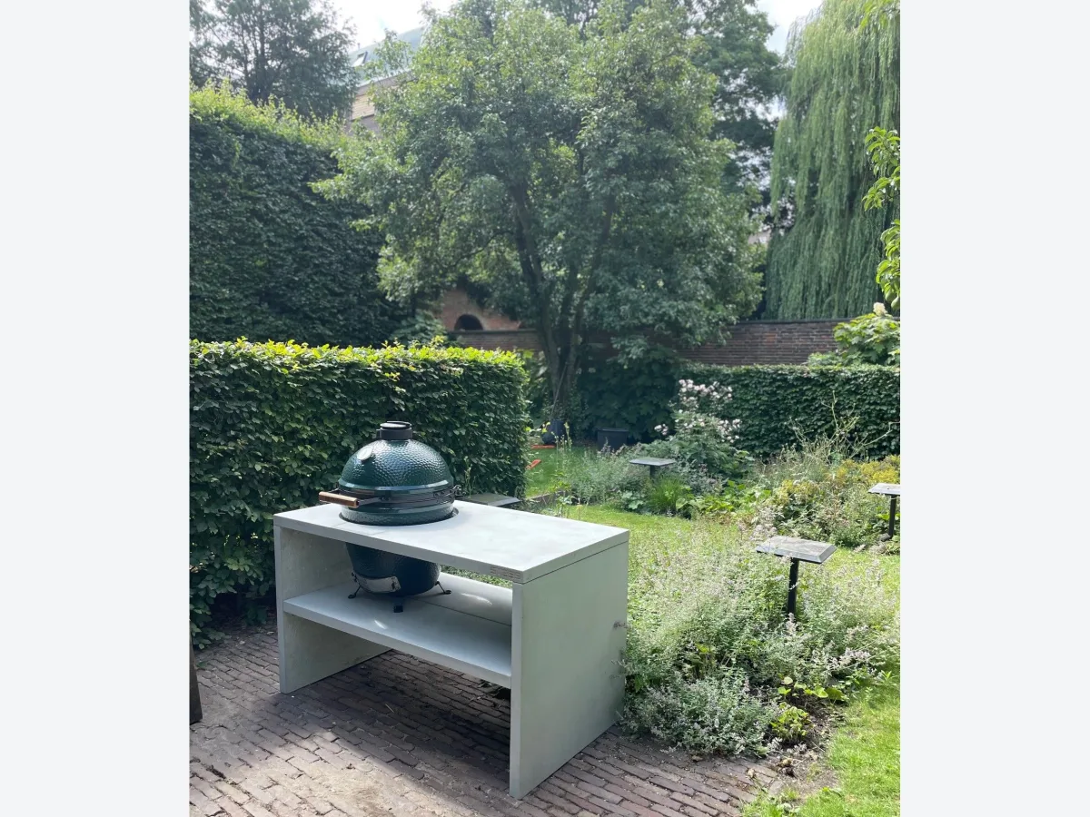 STEGG STEGG buitenkeuken, Grijze STEGG buitenkeuken met Big Green Egg op een klinkerterras in een groene stadstuin
