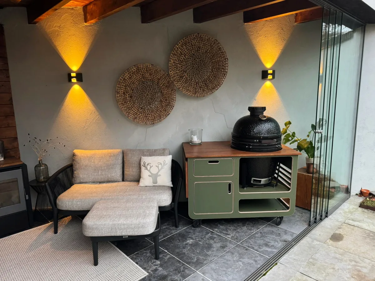 Studio RUUB Buitenkeuken staal en hout, Buitenkeuken staal en hout in olijfgroen met zwarte kamado in een overkapping met loungebank en wandlampen