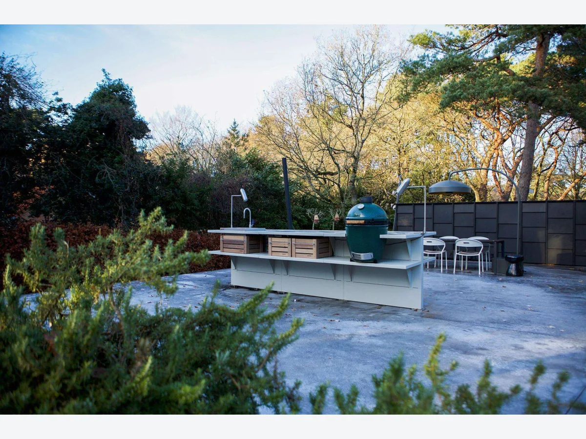 WWOO Staal, WWOO stalen buitenkeuken als vrijstaand kookeiland met Big Green Egg en houten kratten, op een betonnen terras tussen bomen
