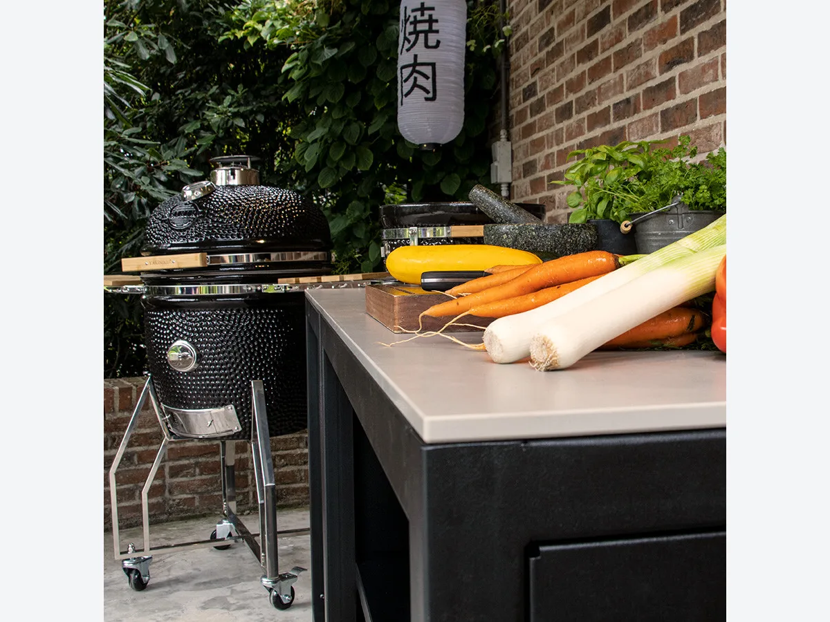 Yakiniku Luxe buitenkeuken, Detail van het werkblad van een Yakiniku Luxe buitenkeuken frame met groenten, met een kamado op onderstel op de achtergrond